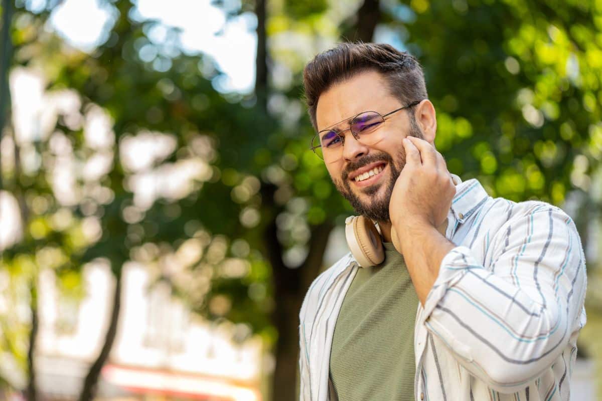 Man holding mouth in pain outdoors