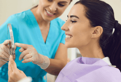 a woman looking at a mirror at the dentist, representing smile makeover in Lansdowne VA