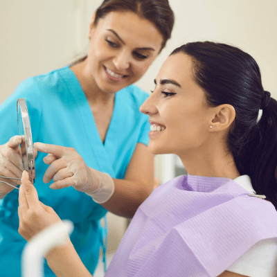 A woman looking at a mirror at the dentist, representing smile makeover in lansdowne va