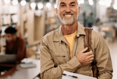 a man holding books and a backpack in a public place while smiling, representing dental crowns in Lansdowne VA