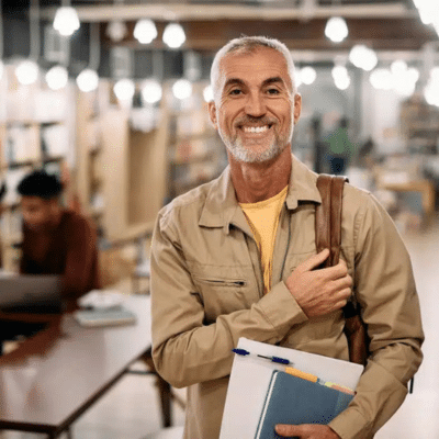 A man holding books and a backpack in a public place while smiling, representing dental crowns in lansdowne va