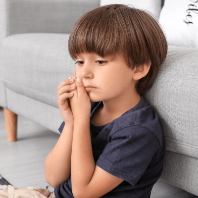 A boy sitting on the floor holding his mouth in pain, representing what to do if your child chips a tooth