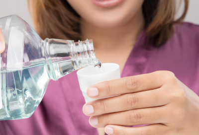 Woman pouring mouthwash into cup, representing how to choose the right toothpaste and mouthwash