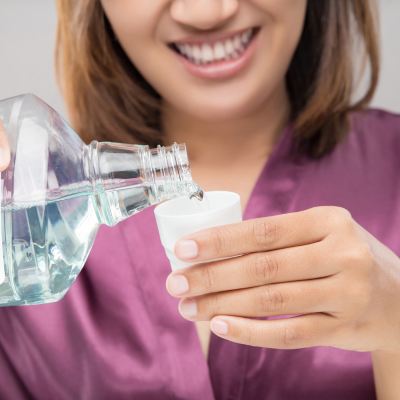 Woman pouring mouthwash into cup, representing how to choose the right toothpaste and mouthwash