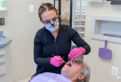 Dr. Brandi Coyle working on an older patient's teeth, representing how to prepare your mouth for dental implants