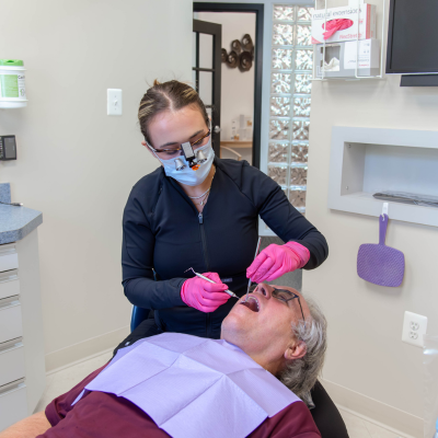 Dr. Brandi Coyle working on an older patient's teeth, representing how to prepare your mouth for dental implants
