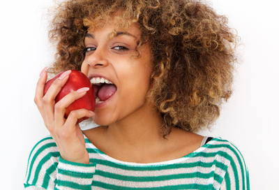 Woman smiling with an apple, representing dental superfoods