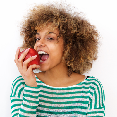 Woman smiling with an apple, representing dental superfoods